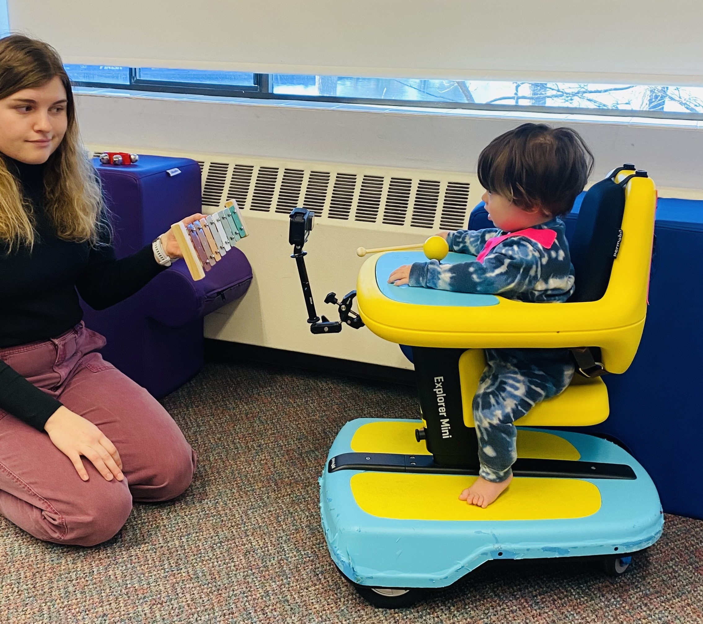 Mia holding a Zylphone while a child sits in Explorer Mini.