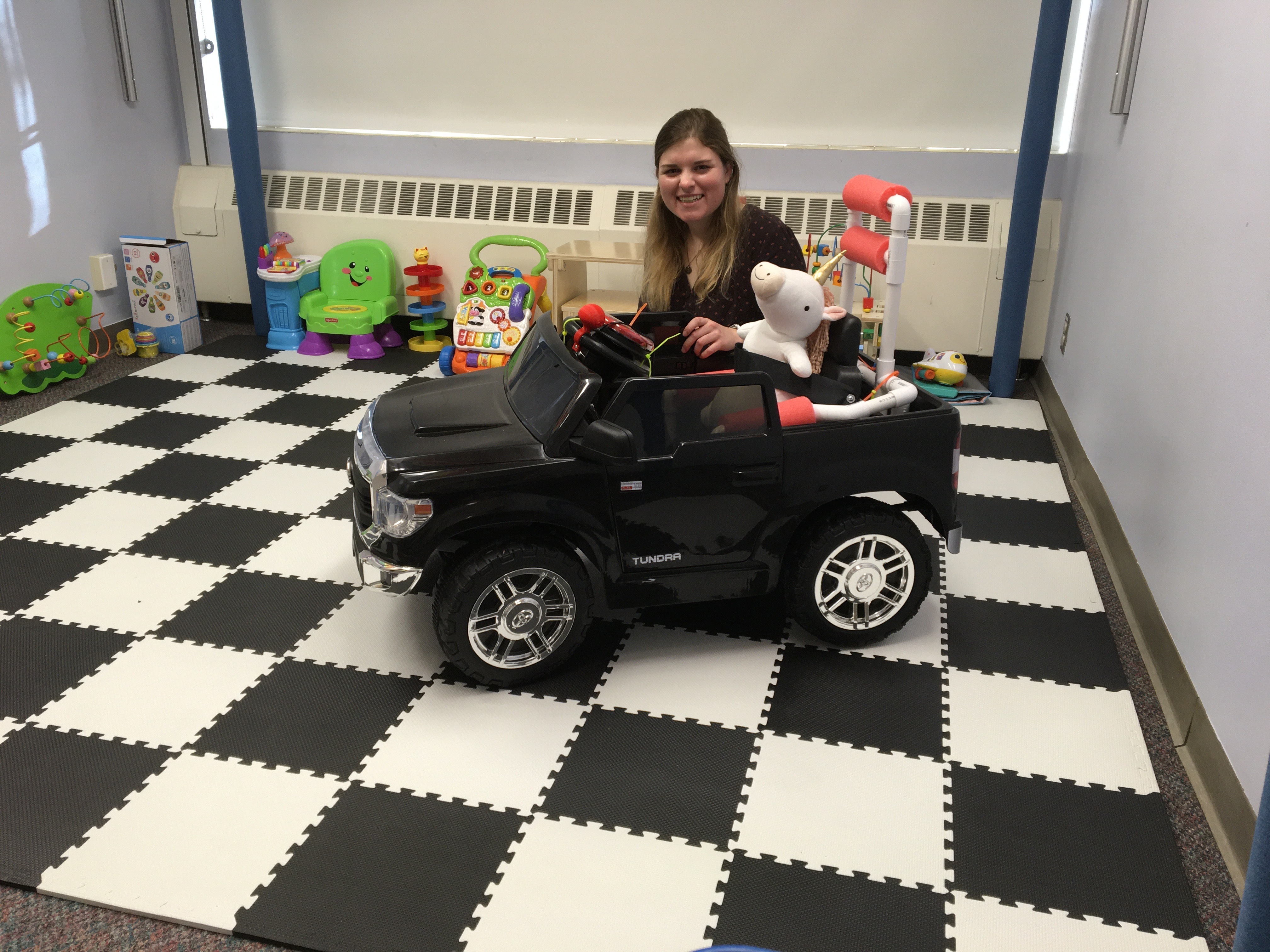 Mia with an adapted ride-on car.