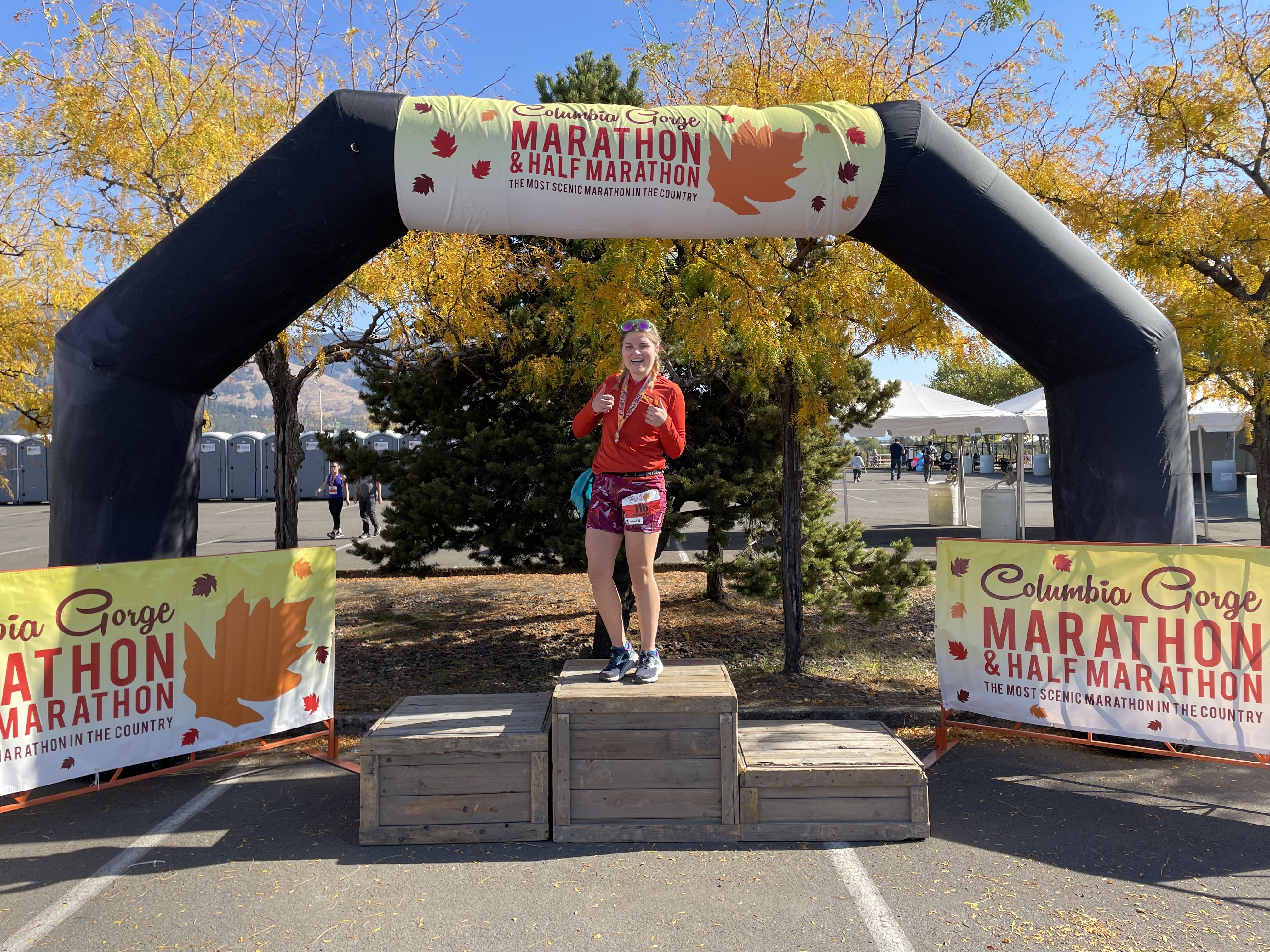 Mia standing on victory steps in front of a half-marathon arch.