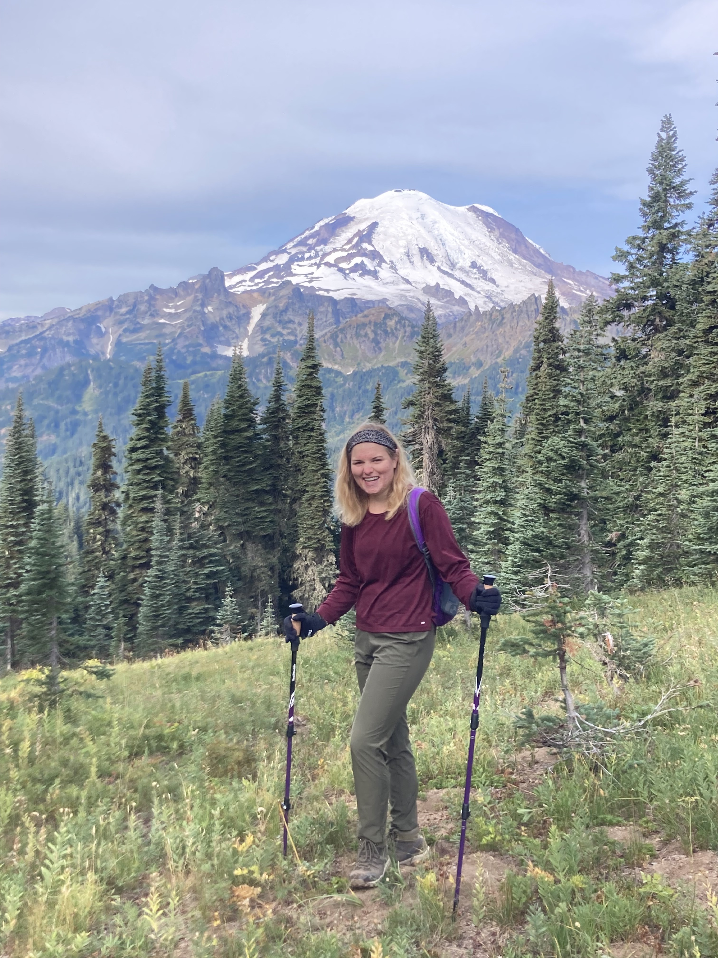 Mia standing holding hiking poles in front of Mt. Rainier.