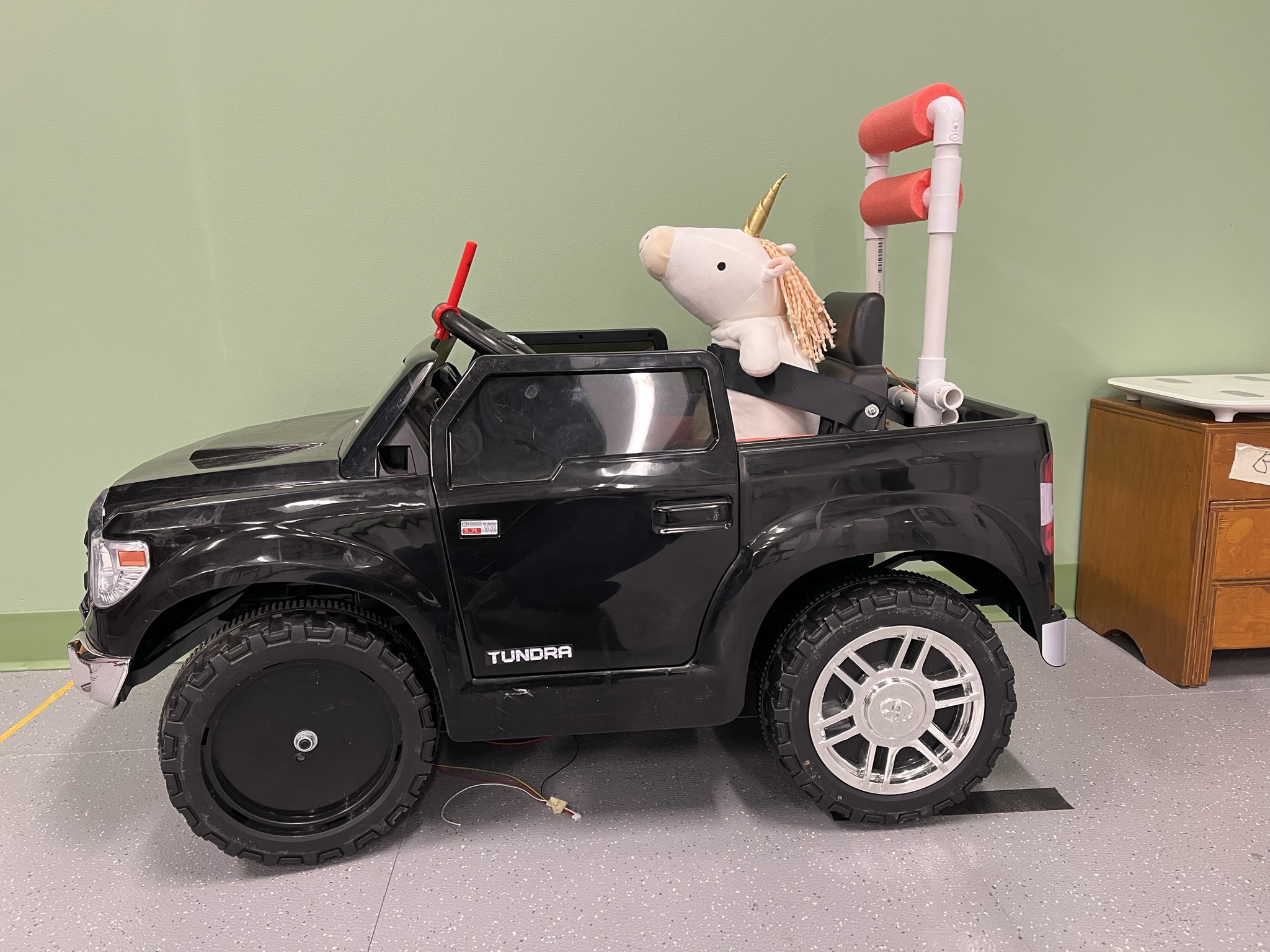 The Research Unicorn sitting in a black Toyota Tundra adapted ride-on car.