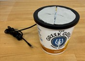 A yogurt container with conductive tape on the lid and a wire coming out of it.